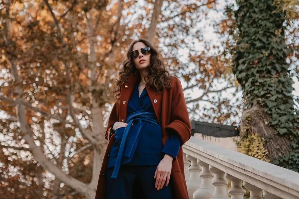 Accueil 13 belle elegante femme maigre souriante aux cheveux boucles marchant dans les escaliers de la rue vetue d un manteau brun chaud et d un costume bleu style de rue a la mode automne 1